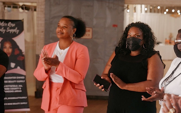 There are 2 woman wearing masks and clapping at an event, they are woman of color who are representing Mungy client: BBEC. Mungy is a Digital Marketing Agency who works with all sizes of companies in the Berkshires and beyond!